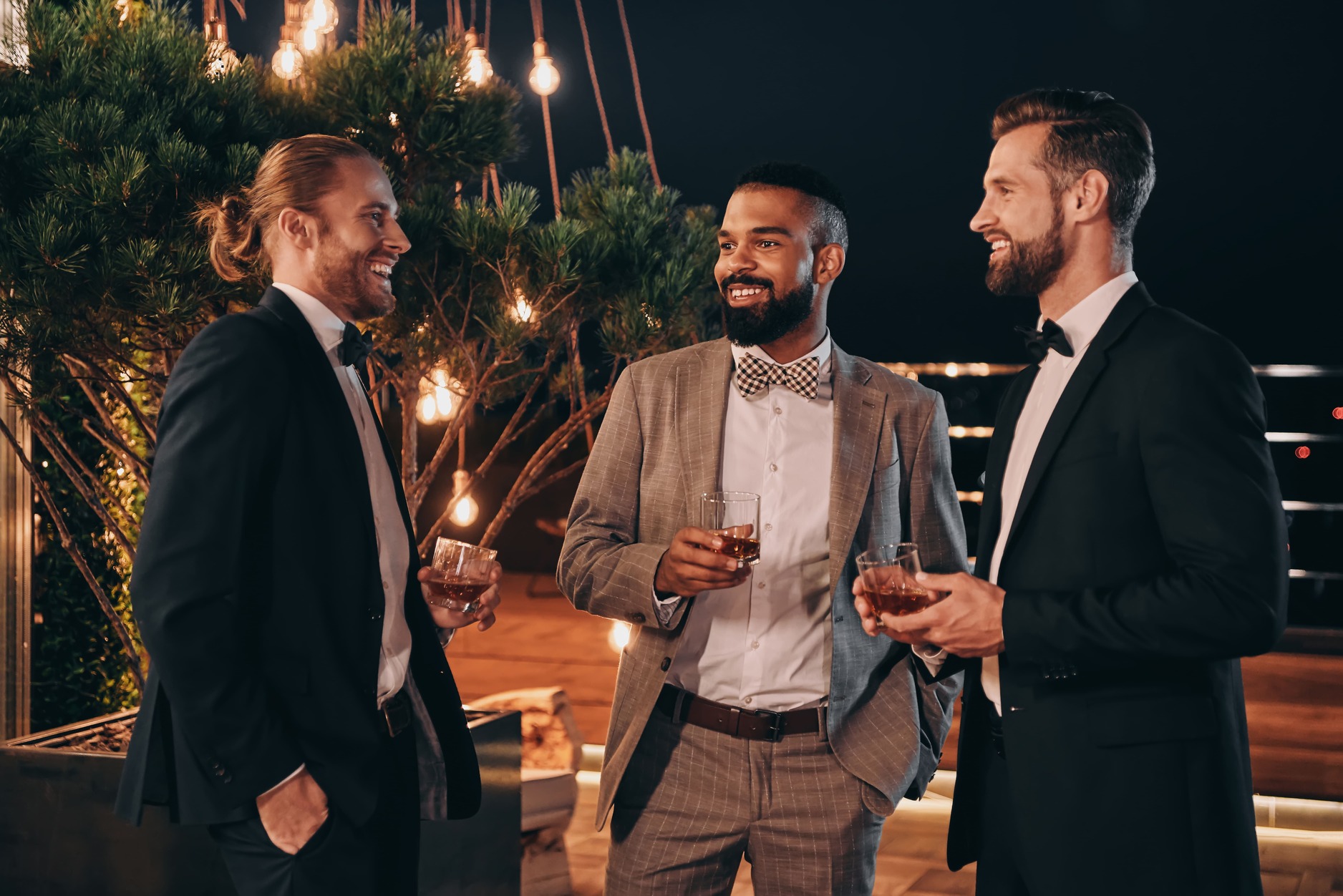 Three elegant young guys drinking wine during a bachelor party