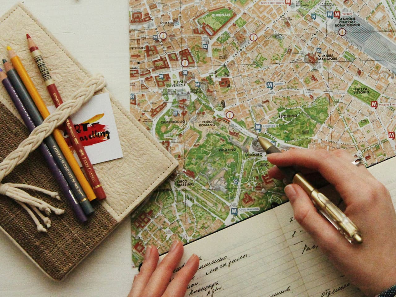 A travel map spread on a desk, with a notebook at hand and colored pencils nearby.
